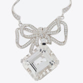Elegant silver necklace with a bow design and a large square gemstone pendant.
